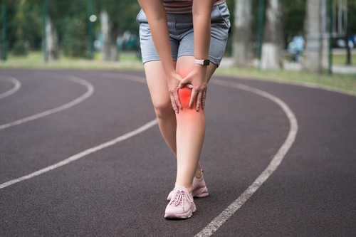 Woman on Track Field With Knee Pain